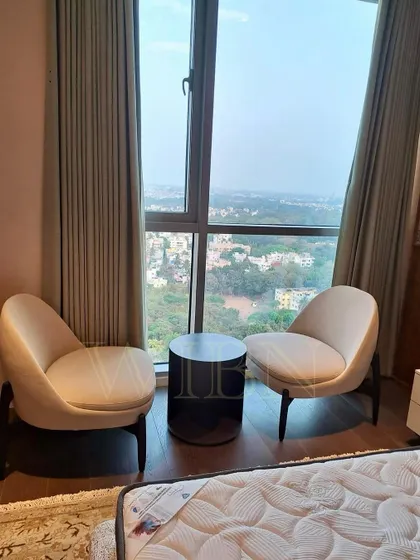 The cozy reading corner in the client's bedroom, featuring our custom chairs and side table. The furniture is perfectly scaled for the space, creating an intimate and functional area.