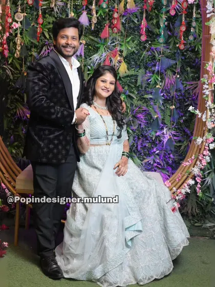 A happy couple at their engagement. The groom-to-be is wearing a black textured tuxedo from my collection, which pairs beautifully with his fiancée's light blue lehenga.