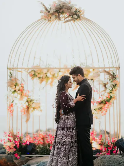 The couple sharing an intimate moment on the rocks by the sea, with their beautiful event decor in the background.