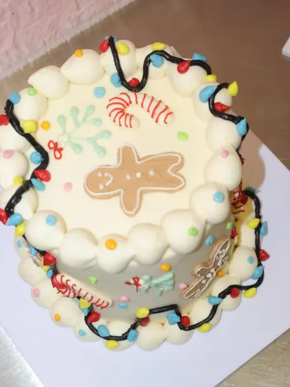 It's beginning to look a lot like Christmas with this festive cake, decorated with a gingerbread man, candy canes, and colorful string lights.