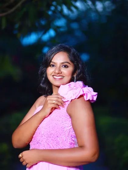 A happy, close-up portrait of a woman in a pink gown, with the soft, out-of-focus garden background adding to the charm.