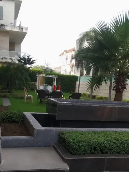 A view of the residential garden featuring a modern, multi-tiered water feature and a seating area in the background. I integrate elements like water features and seating to make gardens more enjoyable.