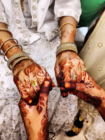 A lovely, connected pose showing the beautiful henna stain on both individuals.