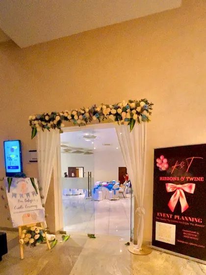 The entrance to the cradle ceremony, decorated with a floral garland, white drapes, and our company standee.