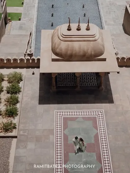 Another perspective of the drone shot, showing the couple's small figures against the vast, patterned palace grounds.