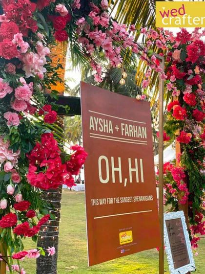 Let the Sangeet shenanigans begin. This fun "Oh, Hi" sign, framed by vibrant red and pink flowers, directed guests to the party at a lively beachside Sangeet.