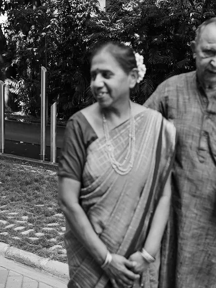 A classic black and white portrait of grandparents, made even more special by the joyful photobomb from their grandchild in the background. It's a perfect, unscripted family moment.