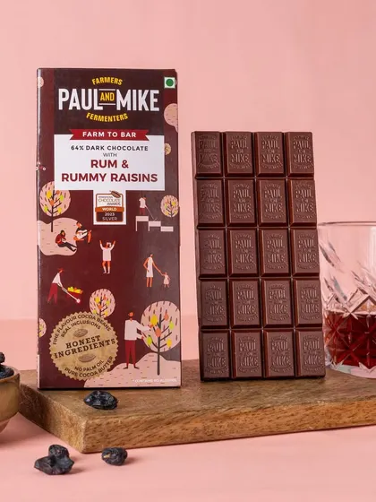 A Rum & Raisin dark chocolate bar styled with a glass of rum, perfectly capturing the essence of its flavor profile.