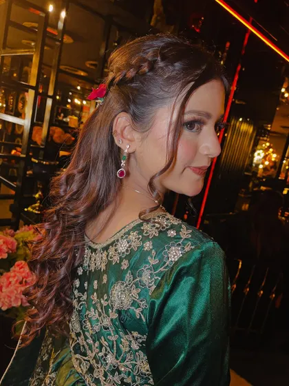 Another view of the beautiful hairstyle, showing how the curls cascade down the back. This style adds volume and movement, making it a great choice for a lively event like a sangeet.