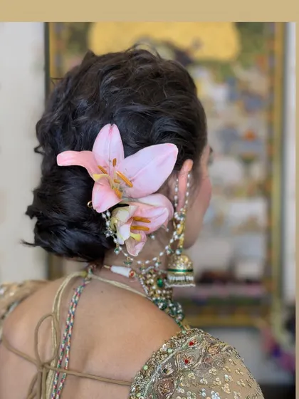 A slightly different angle of the lily-adorned messy bun, showing how the flowers are nestled into the hair for a natural, organic feel.