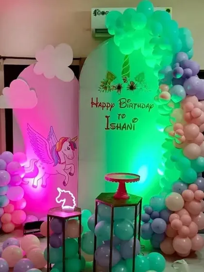 A magical unicorn theme with a winged unicorn backdrop and a neon light effect. The pastel balloons and small neon unicorn sign complete the look.