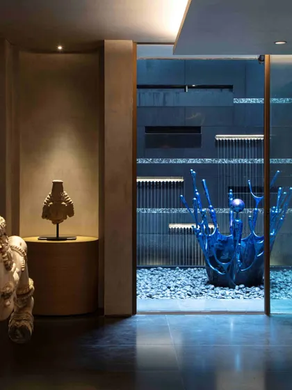 The view from the lobby into the open-to-sky courtyard, where an antique wooden horse from Kutch stands in dialogue with the modern blue water sculpture. This juxtaposition of old and new is central to our design philosophy.