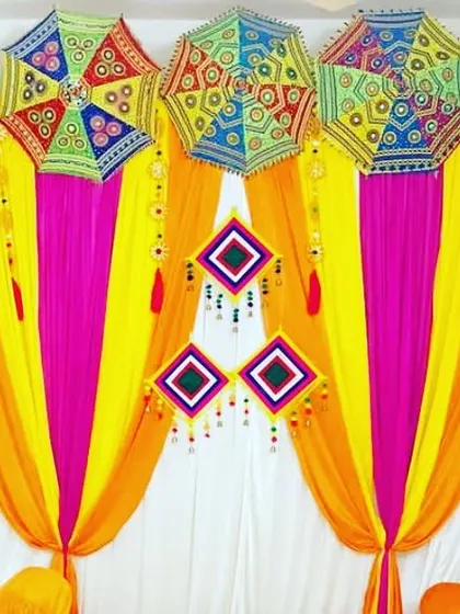 A close-up of a colorful backdrop made with orange, yellow, pink, and white drapes, perfect for a vibrant Mehendi or Sangeet party.