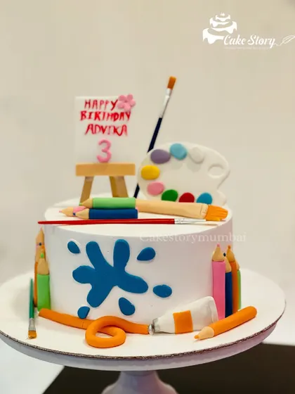 A cake for a budding artist. This design features a mini easel, a paint palette, brushes, and color pencils, all made from edible fondant.