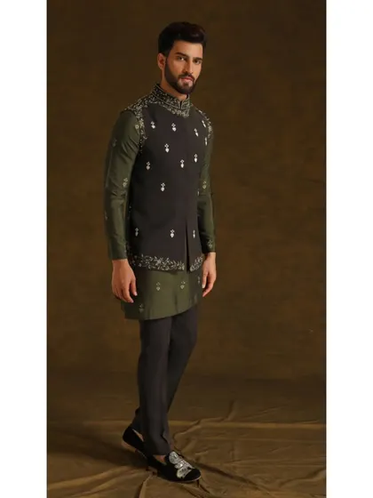 The 'Vedik Vigyaan' ensemble. This look pairs a dark olive asymmetrical kurta with a charcoal grey embroidered Bandi jacket, creating a sophisticated, earthy-toned outfit.