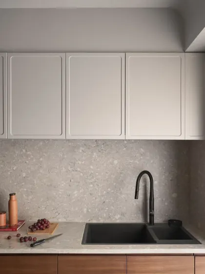 The kitchen countertop and backsplash are made from a durable and beautiful grey terrazzo. Paired with a modern black sink and faucet, the look is clean, timeless, and practical.