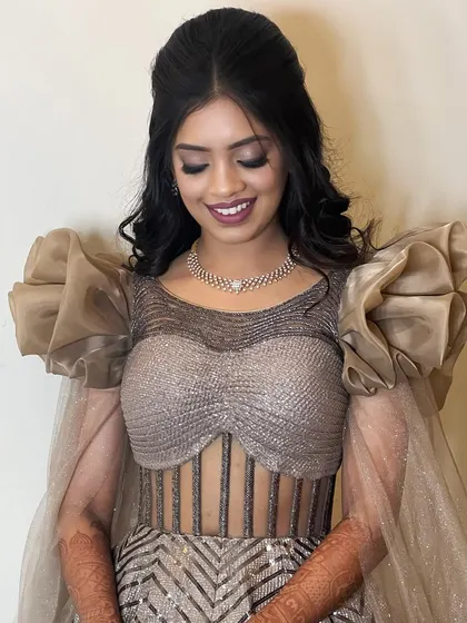 A beautiful, happy client showing off her party-ready look. The dramatic sleeves of her outfit are balanced by a sophisticated makeup and hair combination.