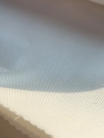 The subtle texture of a white-on-white striped fabric, adding a touch of visual interest to a classic white shirt.