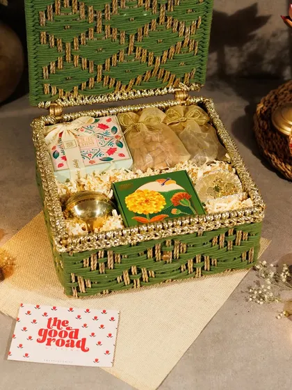 An open view of the green and gold Diwali hamper, showing the arrangement of gourmet snacks and traditional decor items. It’s a perfect blend of taste and tradition.