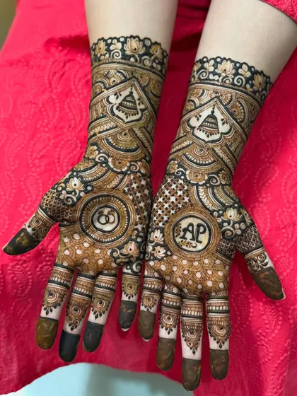 The rich, dark stain of a personalized engagement mehendi, highlighting the couple's initials 'AP' and intertwined rings.