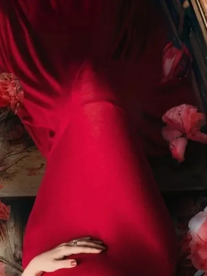 A beautiful abstract shot focusing on the rich red fabric and the mom-to-be's hand on her bump. This highlights the artistic details of a themed maternity shoot.