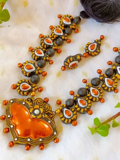 The butterfly-pendant necklace in a warm orange and gold.