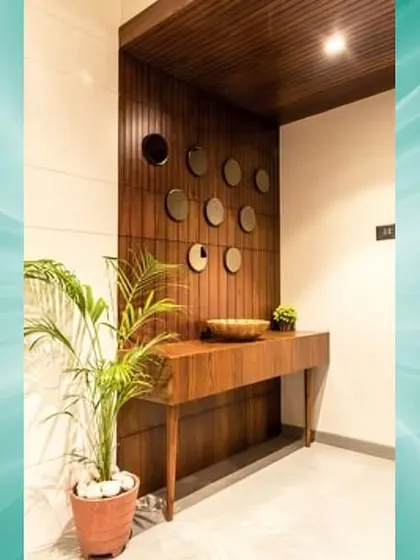 A simple and elegant foyer with a dark wood console table and a wall decorated with small, round mirrors.