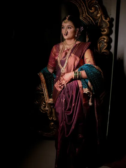 A dramatic, low-key portrait of a bride standing by a decorative frame, using shadows to create a moody and artistic effect.