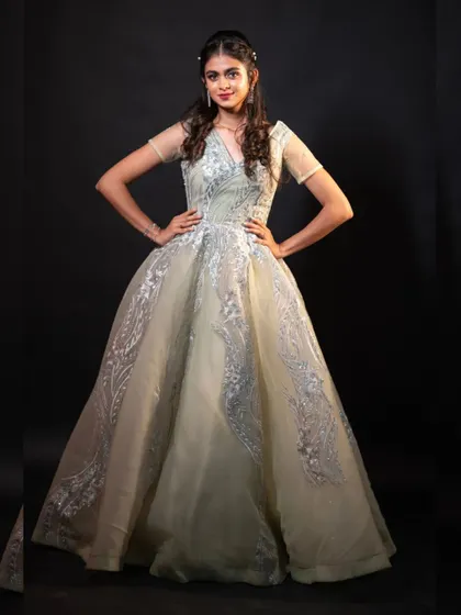 A confident pose showcasing the full silhouette of the pista green ball gown.
