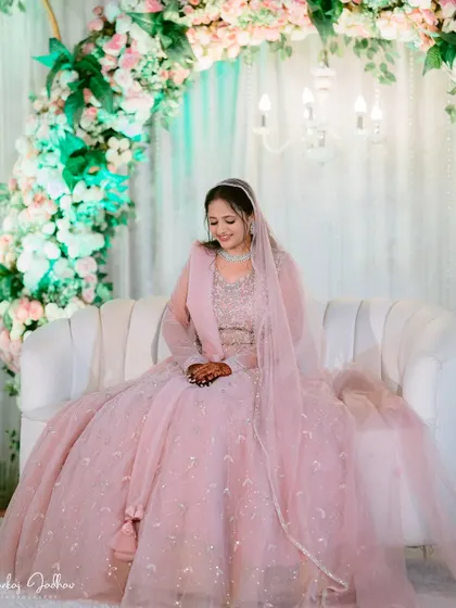 A serene portrait of the bride, Muskaan, seated in front of the beautiful floral decor at her engagement.