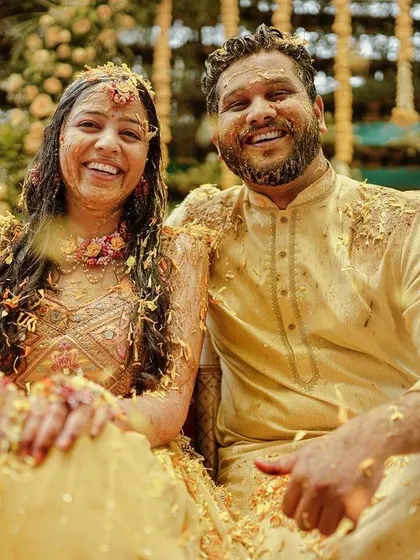 A happy couple covered in flower petals at the end of their fun-filled Haldi ceremony.