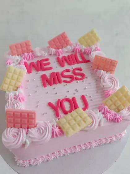 A sweet farewell cake for an office party. The pink design is decorated with mini white and pink chocolate bars.