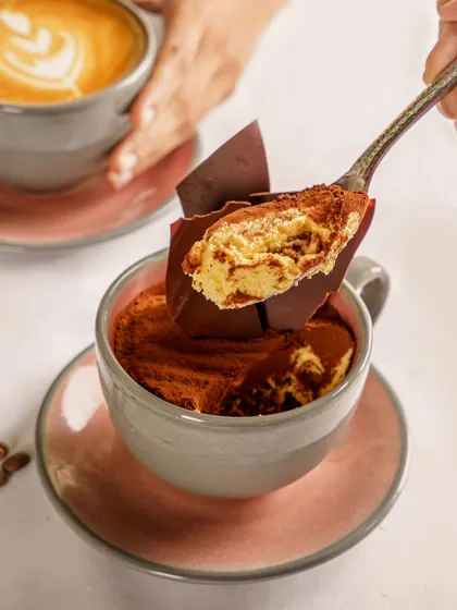 A spoonful of tiramisu being lifted from a coffee cup. This shot is all about the creamy texture and layers, making it an irresistible visual for a cafe's dessert menu.