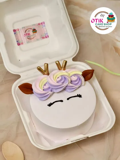 This unicorn bento cake is a perfect little treat. It features a simple, sleepy unicorn face with a crown of pastel-colored frosting roses and golden horns.