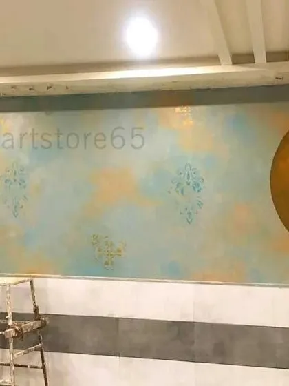 A work-in-progress view of the restaurant wall, showing the scale of the project. The large golden circle is the base for a custom hand-painted logo.