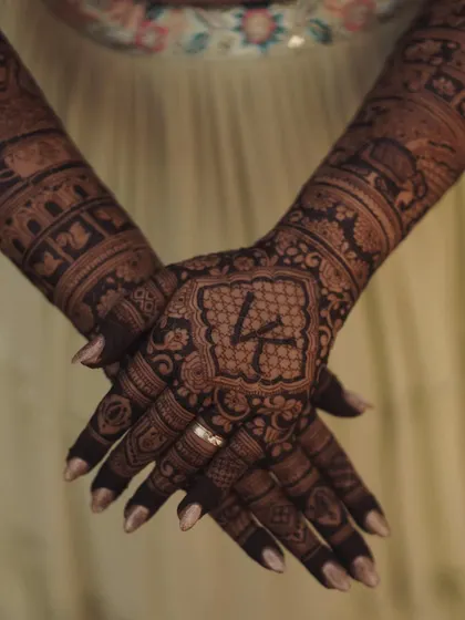 The bride's initial 'K' beautifully placed on the back of her hand, surrounded by intricate patterns. A classic and elegant way to personalize your mehendi.