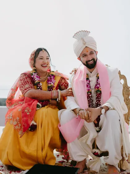 A candid, happy moment of the couple during their wedding ceremony, sharing a laugh while seated together, surrounded by the joy of the occasion.