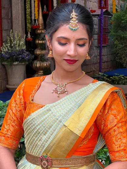 The combination of an orange blouse with a light-colored saree is fresh and modern. You'll learn how to choose makeup colors that tie together unique and contemporary bridal outfits.