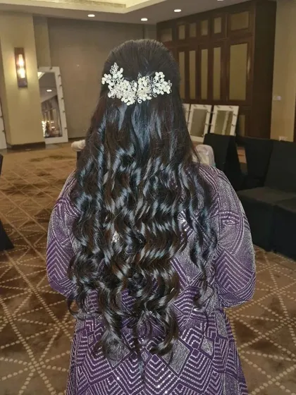 A full back view of the long, curly hairstyle with the intricate hair accessory. This is a statement look for a bride or bridesmaid.