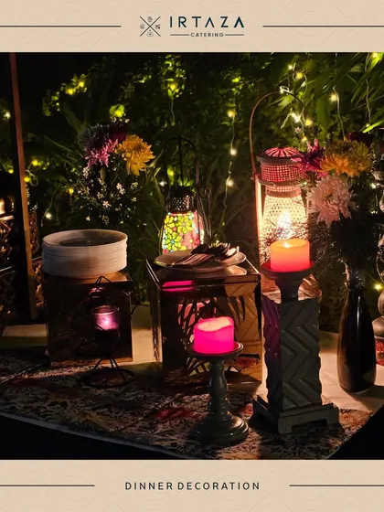 A close-up of a dinner decoration detail. The combination of glowing lanterns, fairy lights, and fresh flowers creates a magical and enchanting ambiance for an evening event.