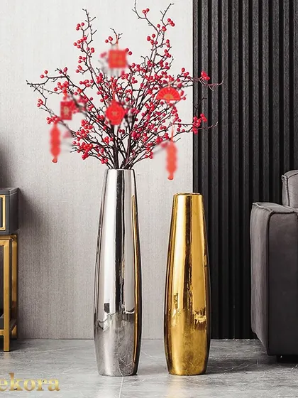 A pair of tall, slender metal vases in polished silver and gold finishes. Their modern, minimalist design makes them a striking addition to a corporate lobby or event space, especially when filled with festive branches.