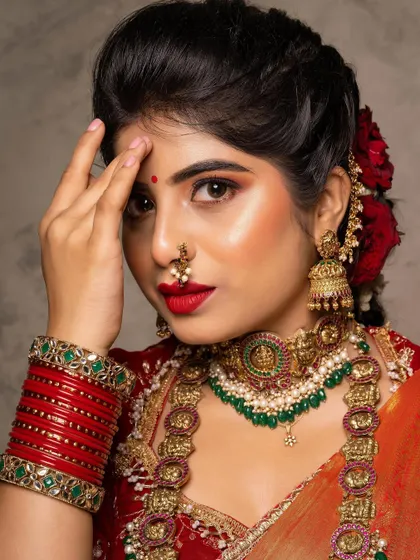 A fresh and glowy look for Shilpa. The bright red lip and rosy cheeks give her a youthful and vibrant appearance, perfectly matching the red flowers in her hair.