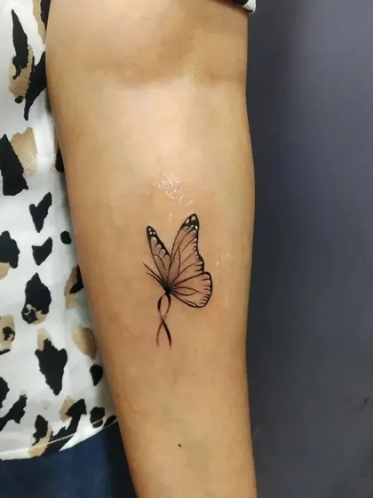 A delicate butterfly tattoo with an infinity loop body. This fine-line design on the inner arm is both elegant and symbolic of endless transformation.
