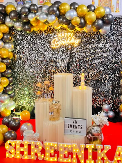 For a touch of glamour, our sequin shimmer walls are a great choice. This birthday setup combines a sparkling silver wall with a black and gold organic balloon garland, marquee letters, and a neon sign for a chic and modern party look.