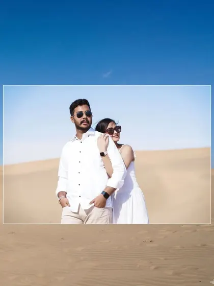 A cool and casual portrait of the couple in the desert, wearing sunglasses and white outfits, exuding a relaxed and stylish vibe.
