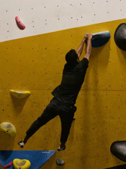 A climber stretches to reach a distant hold, showcasing the flexibility and body awareness we train for in our advanced bouldering classes.