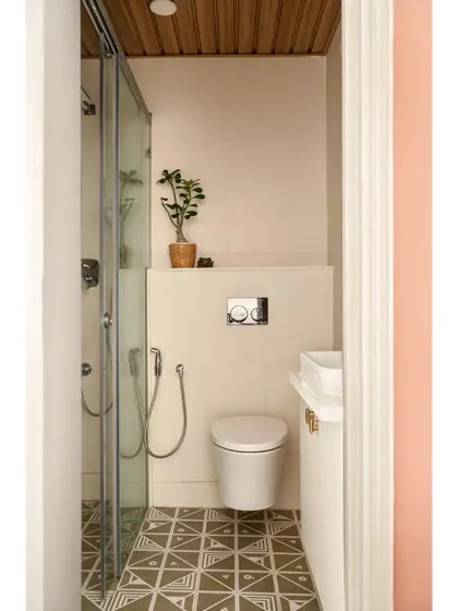The renovated bathroom in the peach guest room, featuring earthy patterned floor tiles and a wooden ceiling. Even in a small space, the design is light, simple, and full of character.