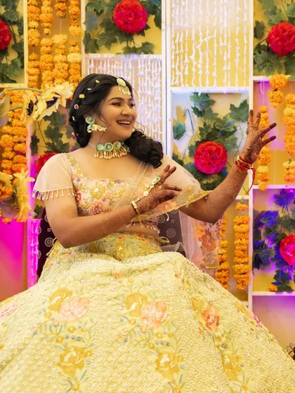 A happy client enjoying her Haldi ceremony. Her makeup is fresh and minimal, with a floral maang tikka completing the look.