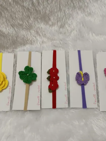 I offer a wide range of custom handmade headbands. This collection shows a variety of designs on soft nylon bands, including a yellow rose, a lucky clover, and a purple butterfly, each made to be gentle on a baby's head.