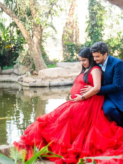 A quiet, tender moment by the water. The way this couple is posed, nestled together in a lush park setting with the vibrant red of her gown, creates a feeling of intimacy and peaceful anticipation.